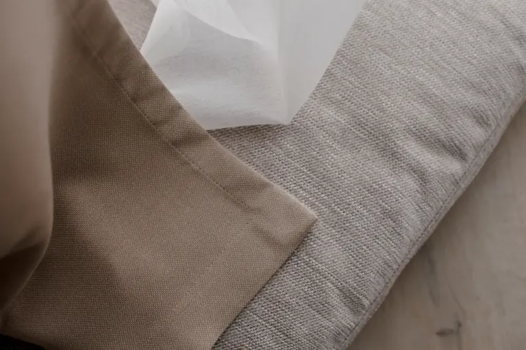 Folded sand and grey curtain fabrics and a white see-through fabric