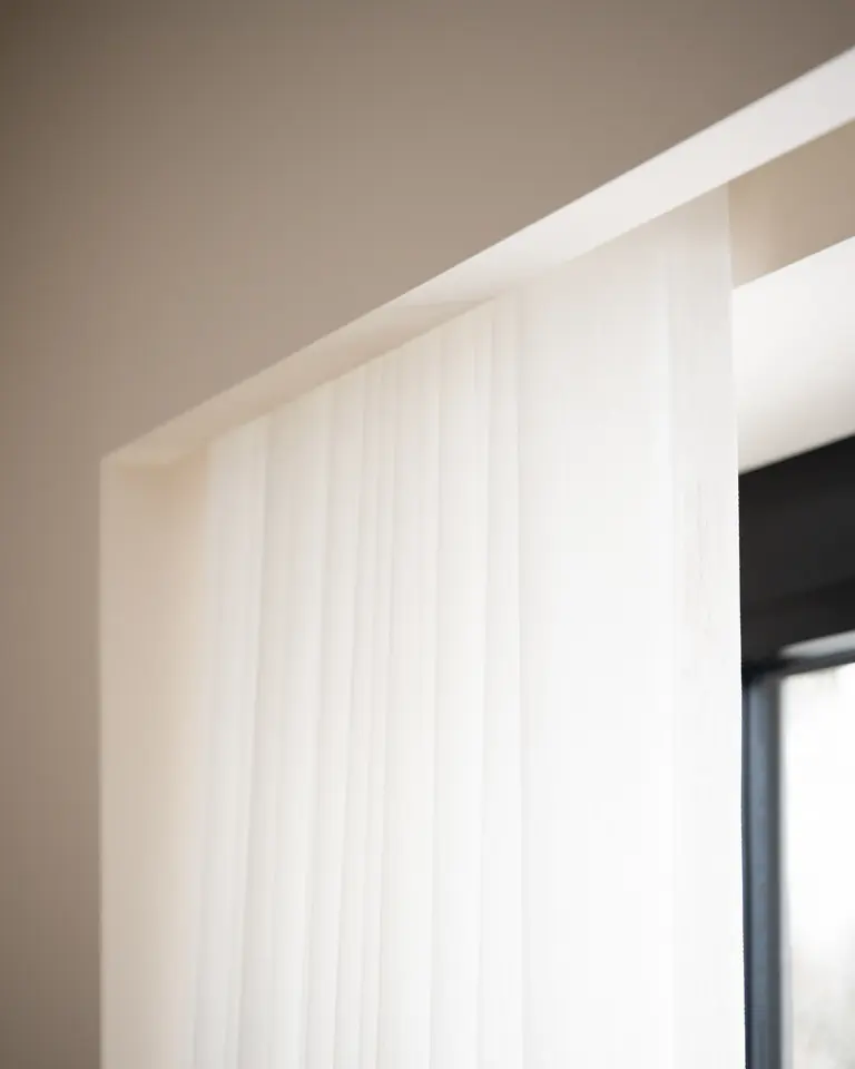 A white see-through fabric hanging from a ceiling recess, with daylight falling through it