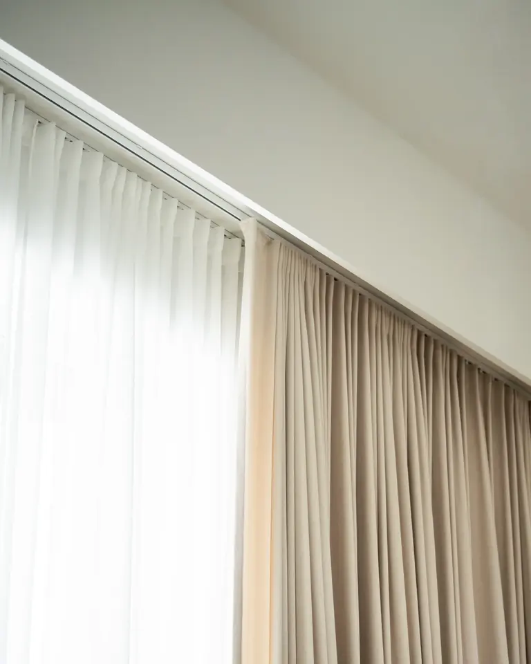 Two layers on ceiling tracks right up at the ceiling: a white sheer and a sand-coloured curtain